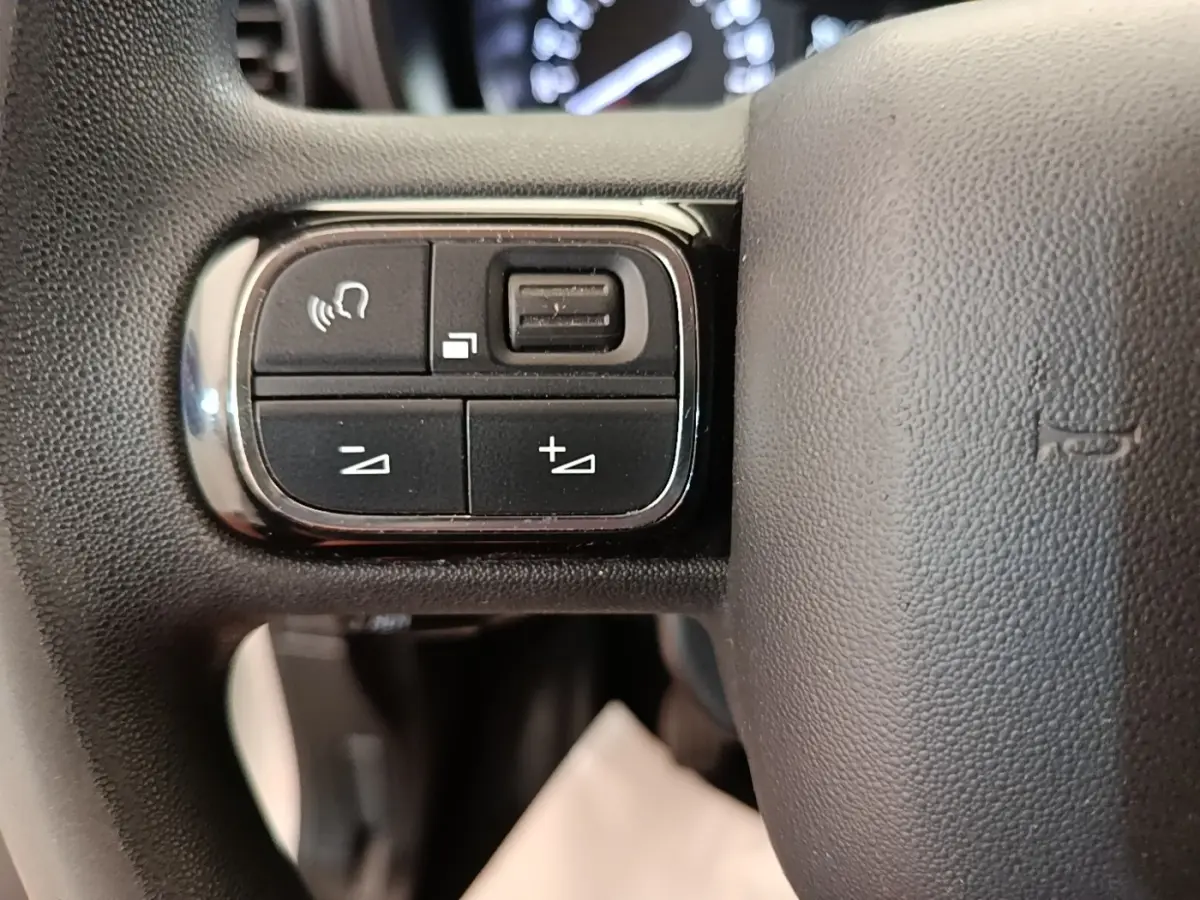 Gros plan sur les commandes multifonctions du volant noir du Citroën Berlingo XL blanc de 2020.