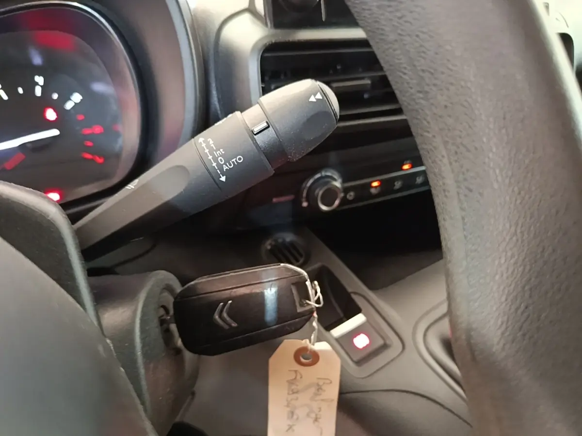 Gros plan intérieur sur le volant et la clé de contact d’un Citroën Berlingo blanc, avec tableau de bord partiellement visible.