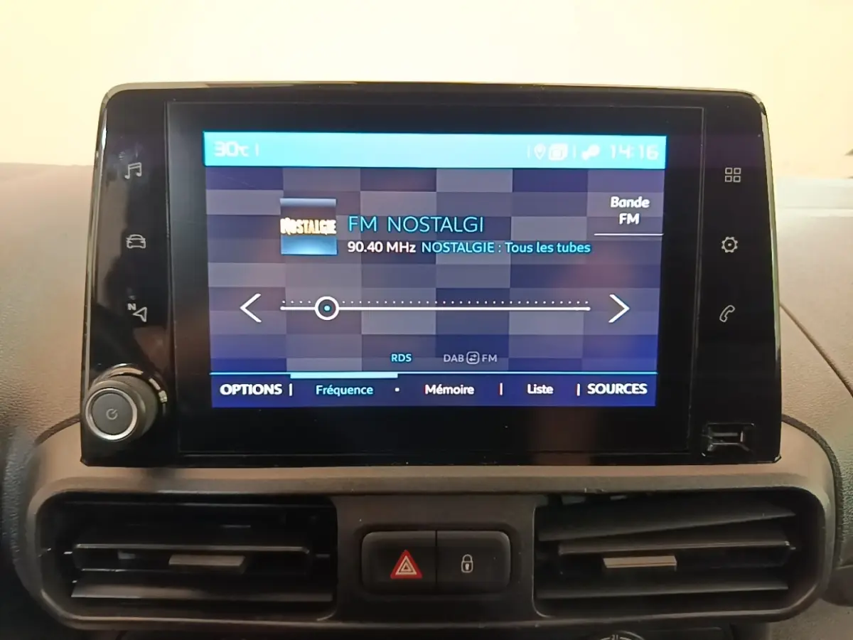 Écran tactile central du tableau de bord du Citroën Berlingo XL blanc, affichant la radio FM Nostalgie.