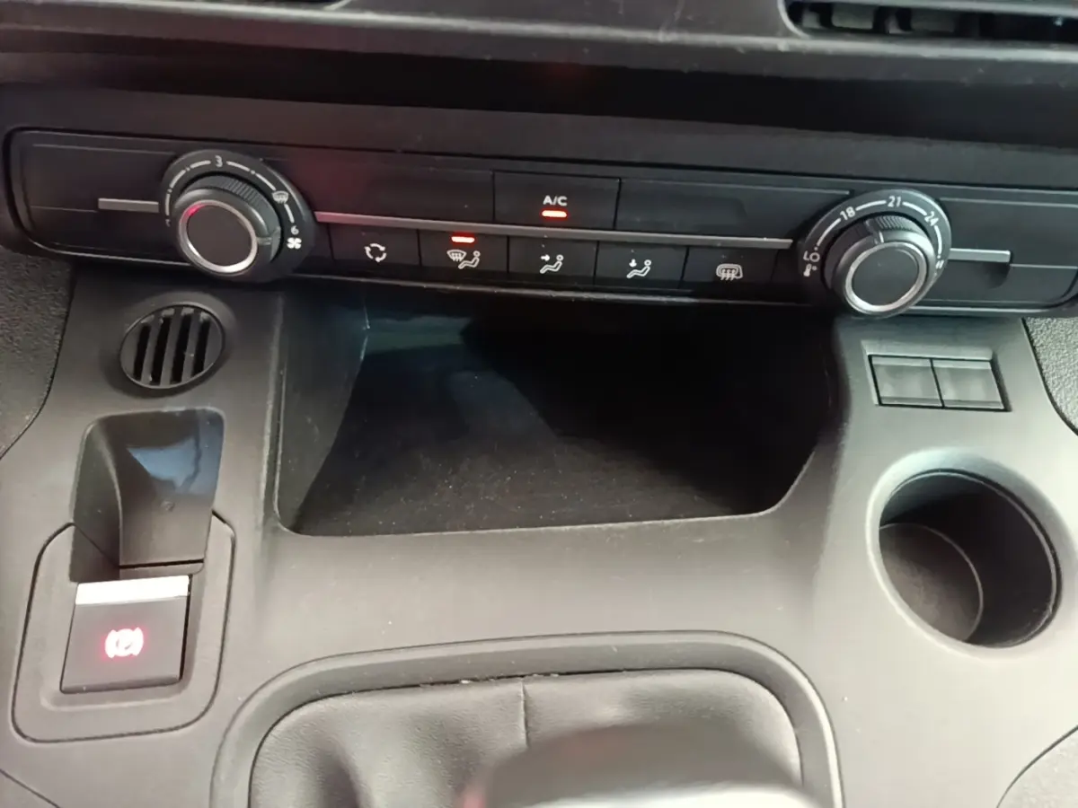 Vue rapprochée de la console centrale noire du Citroën Berlingo XL 2020, avec commandes climatisation et porte-gobelet.