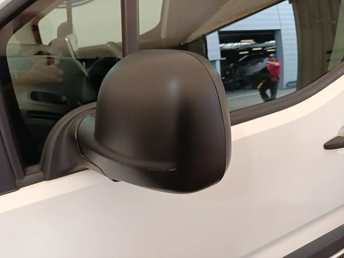 Rétroviseur noir côté gauche d’un Citroën Berlingo XL blanc, vue rapprochée sur la porte avant.