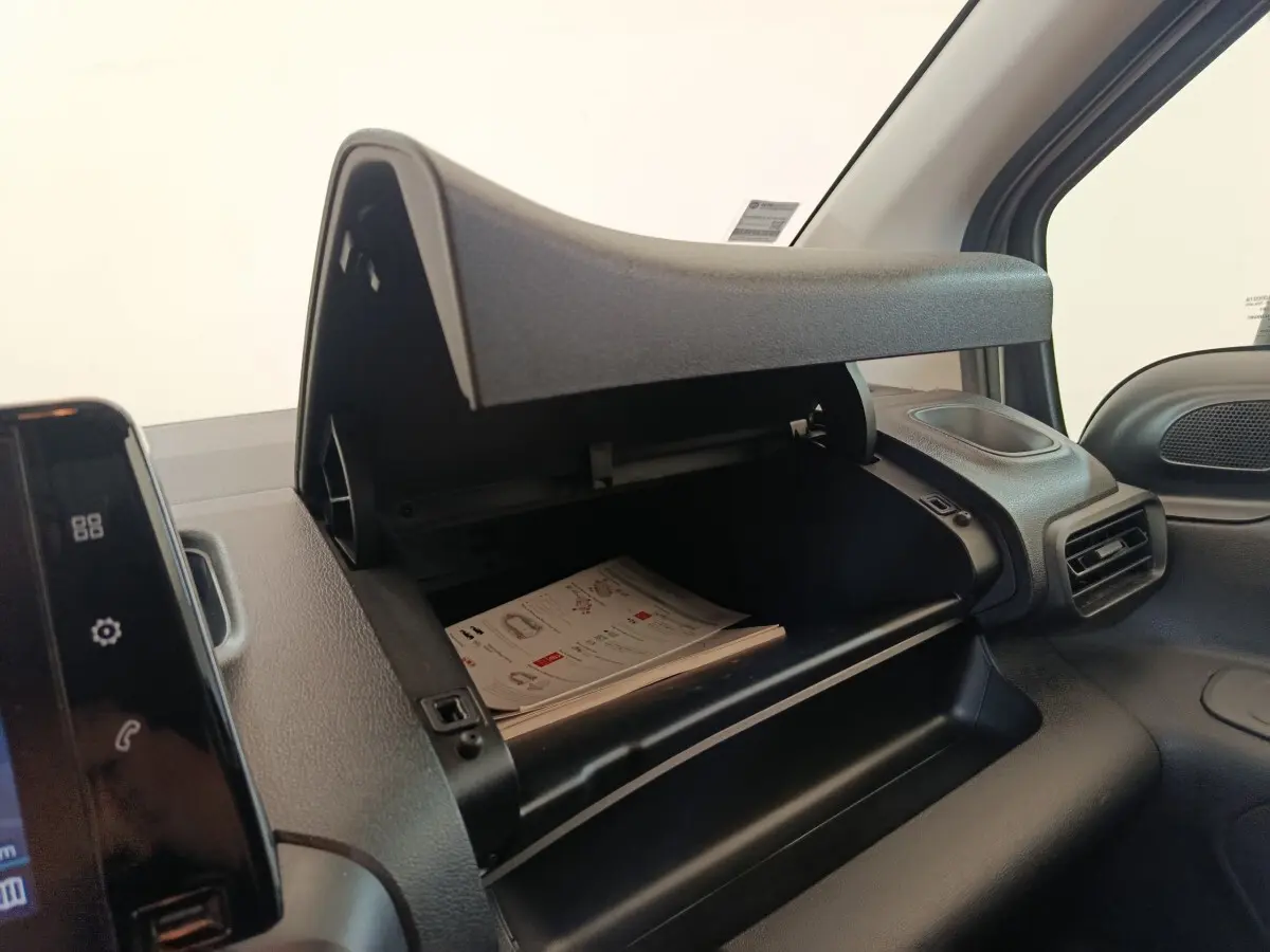 Intérieur du Citroën Berlingo 2020, vue sur la boîte à gants ouverte côté passager avec documents visibles.