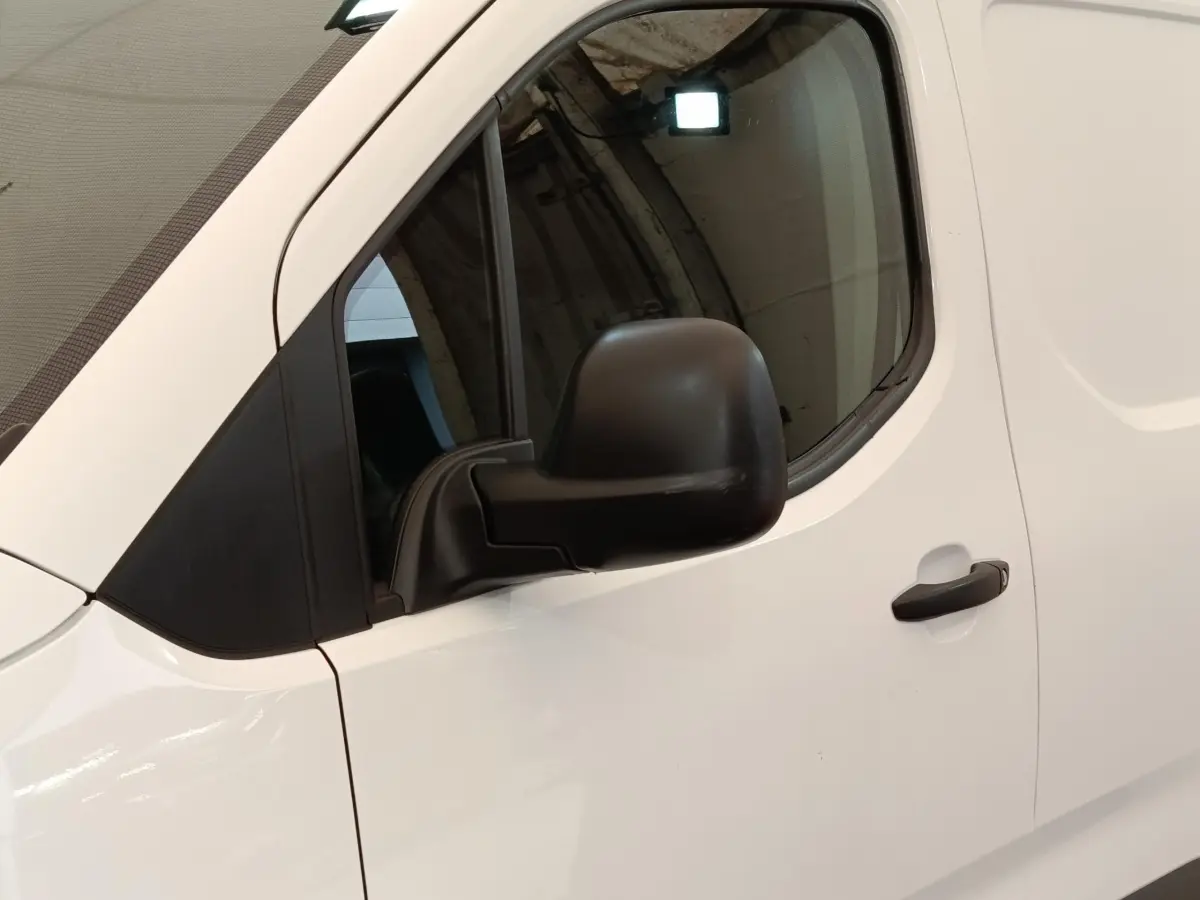 Vue latérale côté conducteur d'un Citroën Berlingo blanc 2020 avec rétroviseur noir et poignée de porte noire.