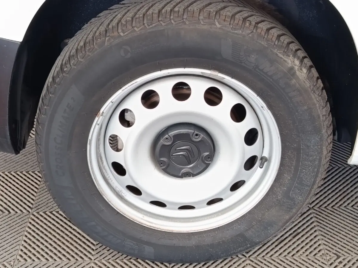 Gros plan sur la roue acier blanche du Citroën Berlingo blanc, montrant le pneu Michelin et le logo Citroën central.