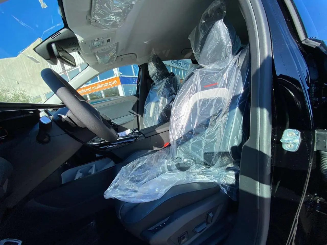 Vue intérieure côté conducteur du Citroën C5 Aircross noir 2026, sièges avant électriques protégés par film plastique.