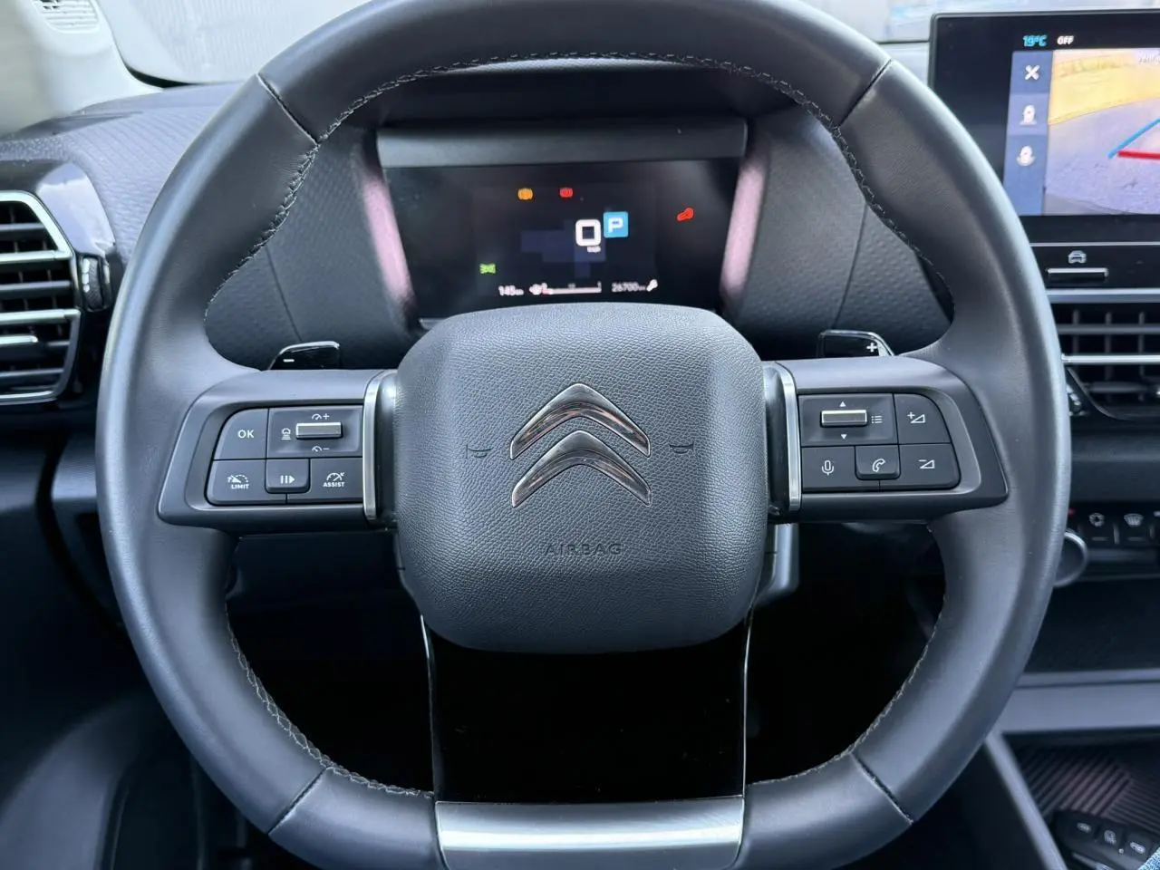 Volant cuir noir de Citroën C4 X 2024 avec commandes intégrées et tableau de bord numérique en arrière-plan.