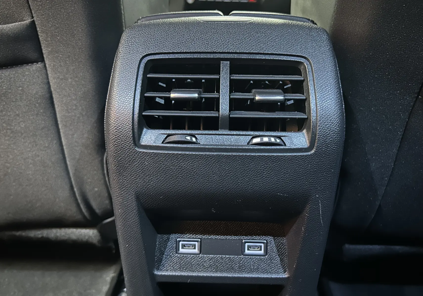 Vue rapprochée de la console arrière noire avec bouches d’aération et deux ports USB de la Peugeot 308 rouge 2024.