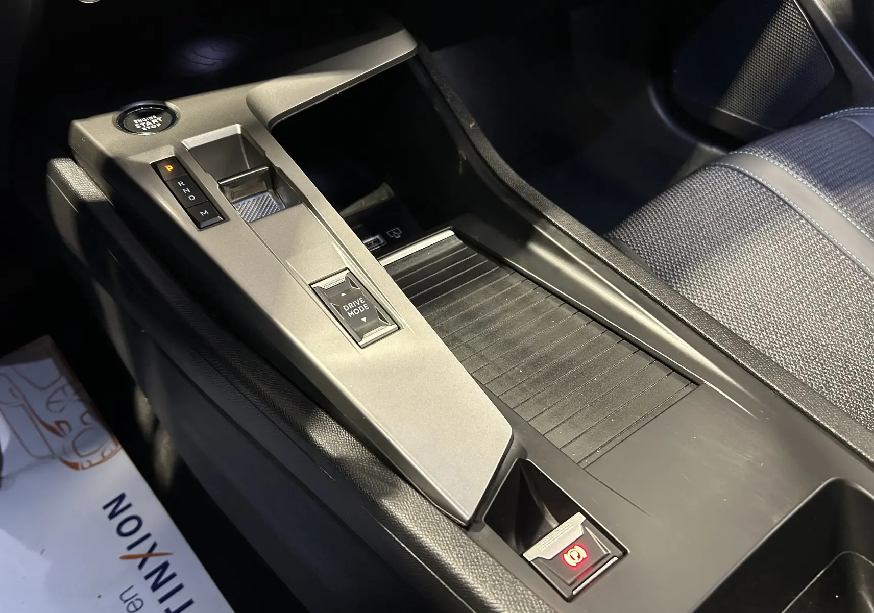 Vue rapprochée de la console centrale grise et noire de la Peugeot 308 2024 avec levier de vitesses automatique et bouton start/stop.