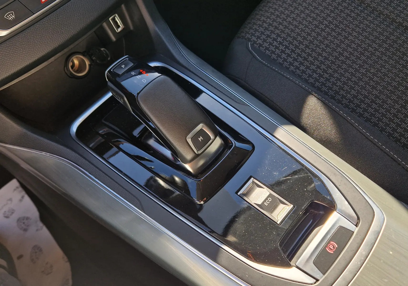 Gros plan sur la console centrale noire de la Peugeot 308 SW 2021, montrant le levier de vitesses automatique et les modes Sport/Eco.