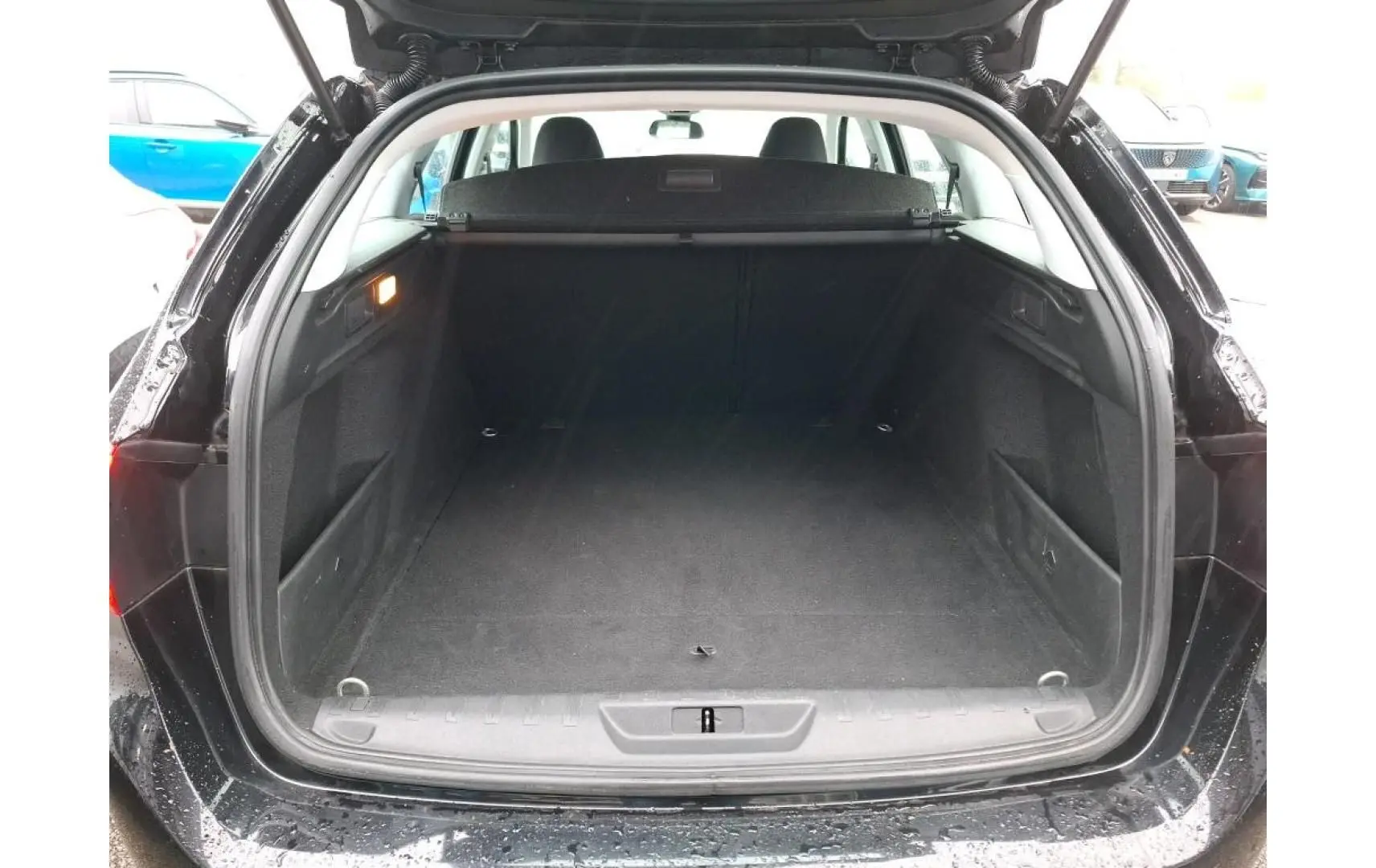 Coffre ouvert vu de l'arrière d'une Peugeot 308 SW noire, montrant un espace de chargement vide et propre.