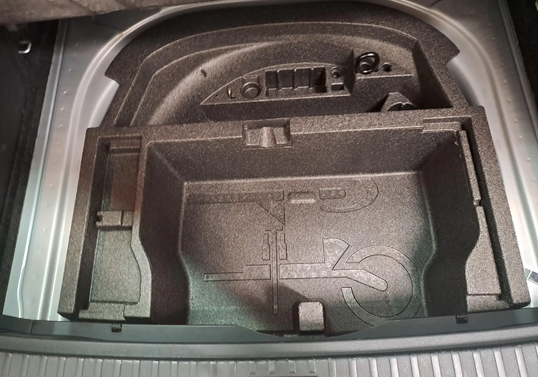 Coffre ouvert vu de dessus montrant le rangement en mousse noir pour outils sur Skoda Octavia Combi gris argent 2025.