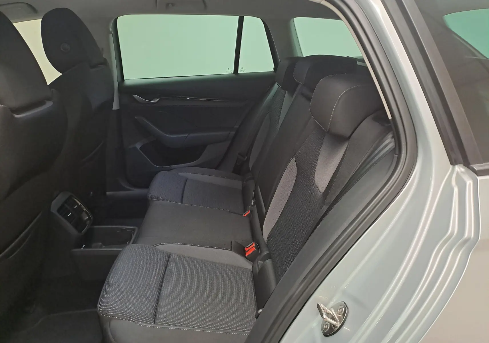Vue intérieure côté droit des sièges arrière en tissu gris d’une Skoda Octavia Combi 2025 gris argent avec porte ouverte.