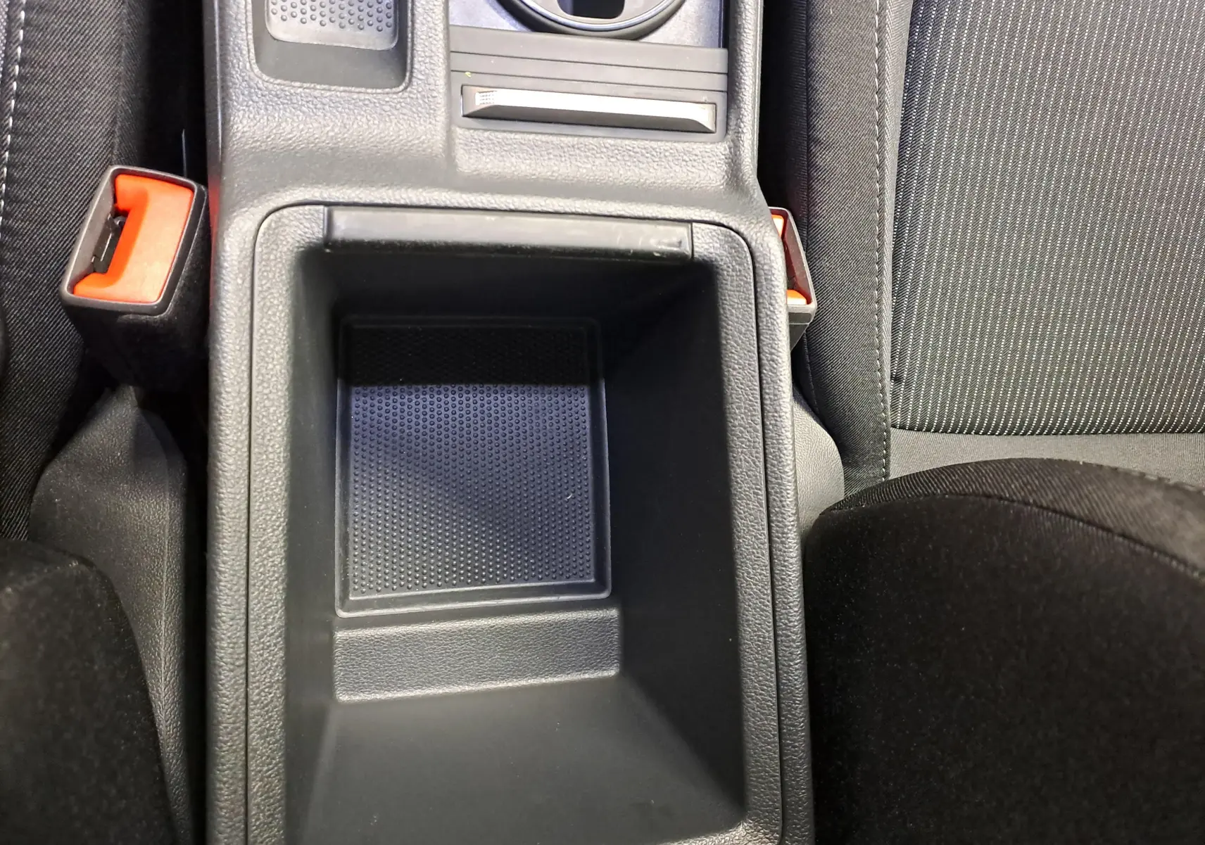 Gros plan sur le rangement central noir entre les sièges avant en tissu gris de la Skoda Octavia Combi 2025.