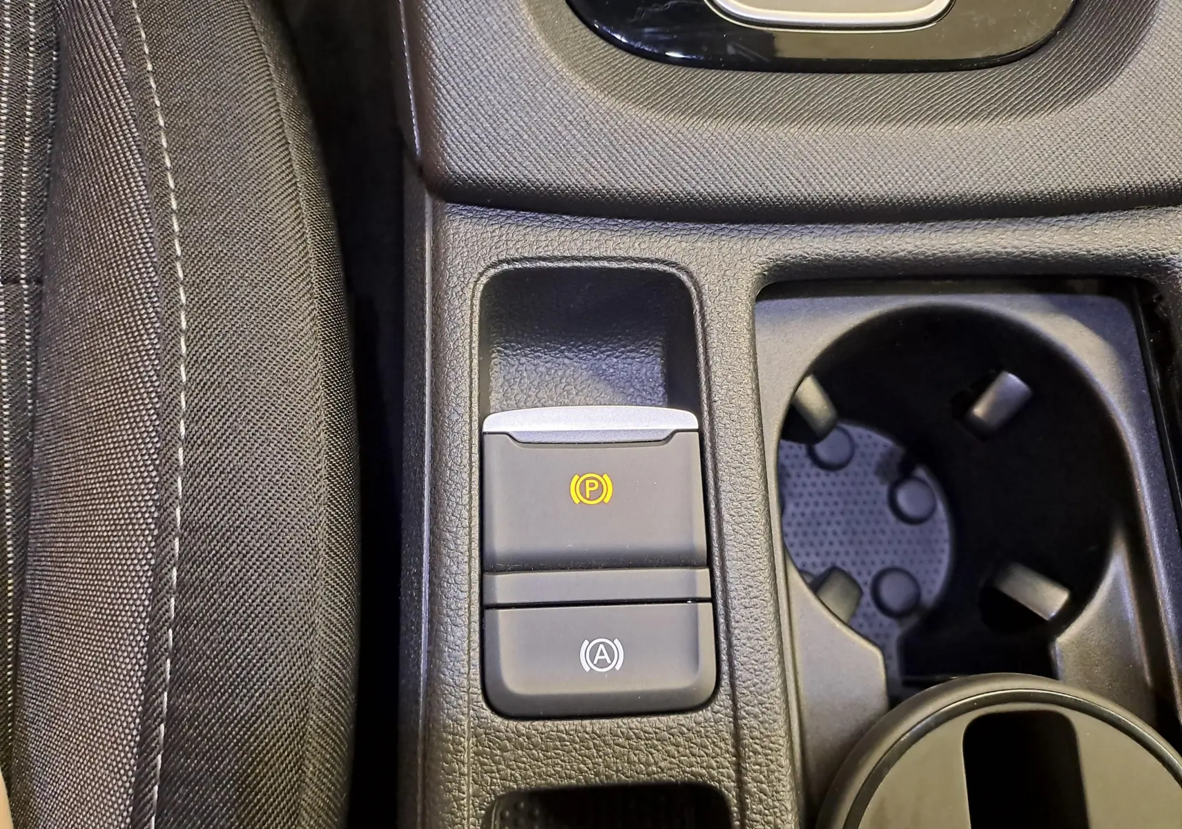 Gros plan sur la console centrale de la Skoda Octavia Combi 2025, boutons frein à main électronique et auto hold visibles.