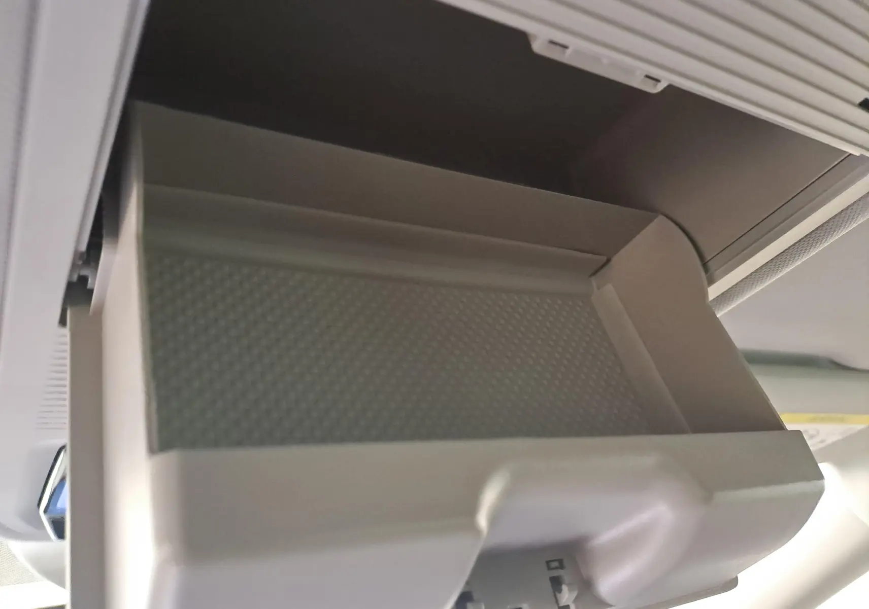 Gros plan sur le rangement plafond ouvert de la Skoda Octavia Combi 2025, intérieur gris clair, détail fonctionnel visible.