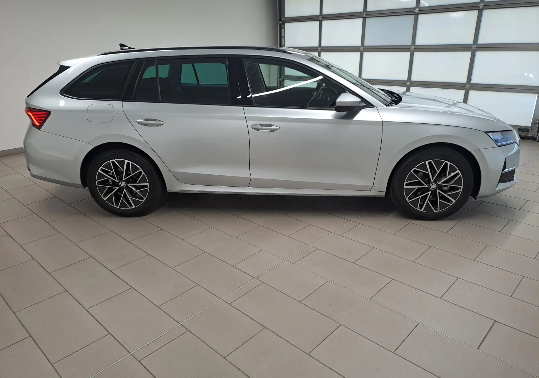 Vue latérale droite d'une Skoda Octavia Combi 2025 gris argent avec jantes alliage noires polies et vitres surteintées.