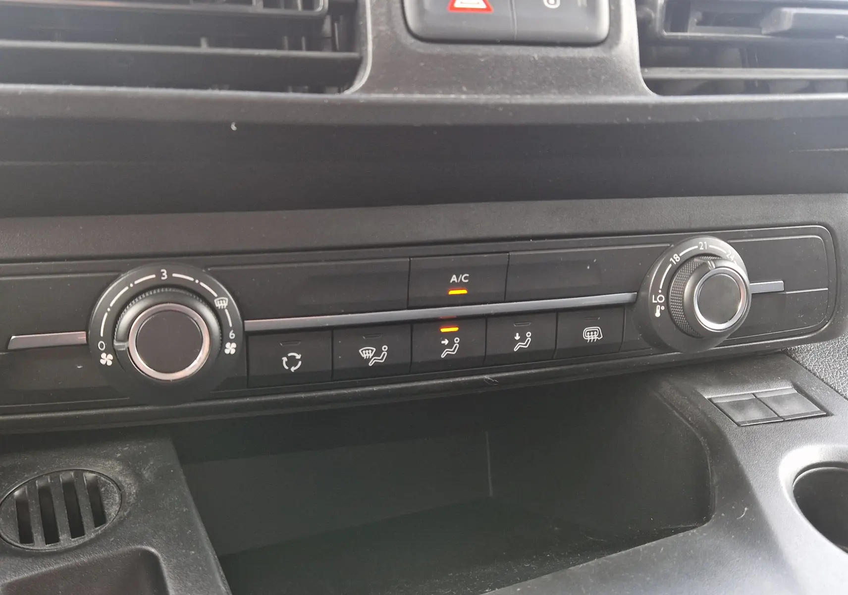 Gros plan sur la console centrale du Peugeot Partner blanc 2021, montrant les commandes de climatisation et ventilation.