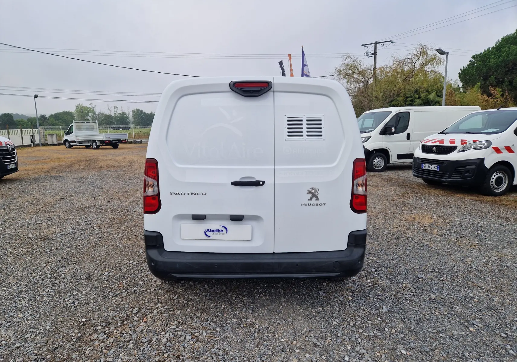 Vue arrière d’un utilitaire blanc Peugeot Partner Long 2021 avec logo et marquage VitalAire sur porte droite.