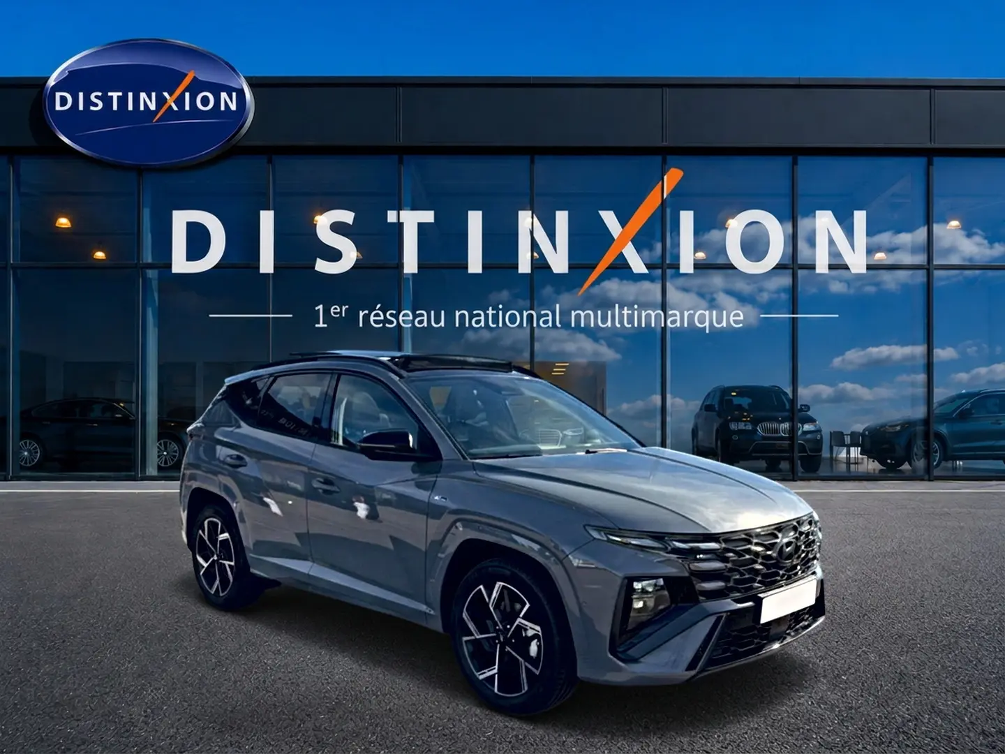 Hyundai Tucson 2026 gris shadow en 3/4 avant droit, avec calandre noire et jantes alu distinctives.