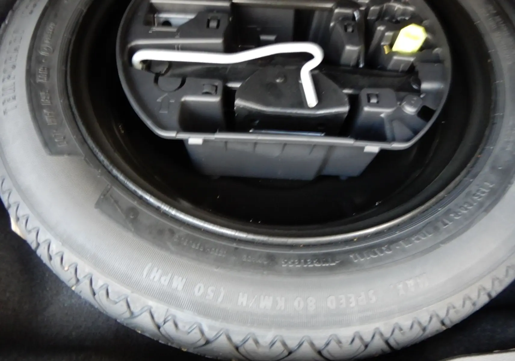 Gros plan sur la roue de secours et la boîte à outils noire dans le coffre d'une Peugeot 508 SW noire.