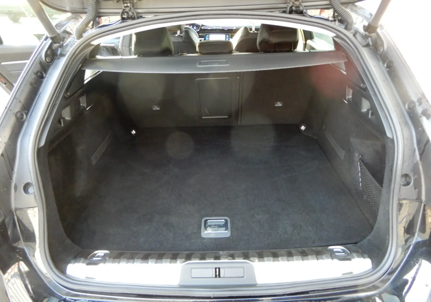 Coffre ouvert en vue arrière d'une Peugeot 508 SW noire, montrant un espace de chargement spacieux et propre.