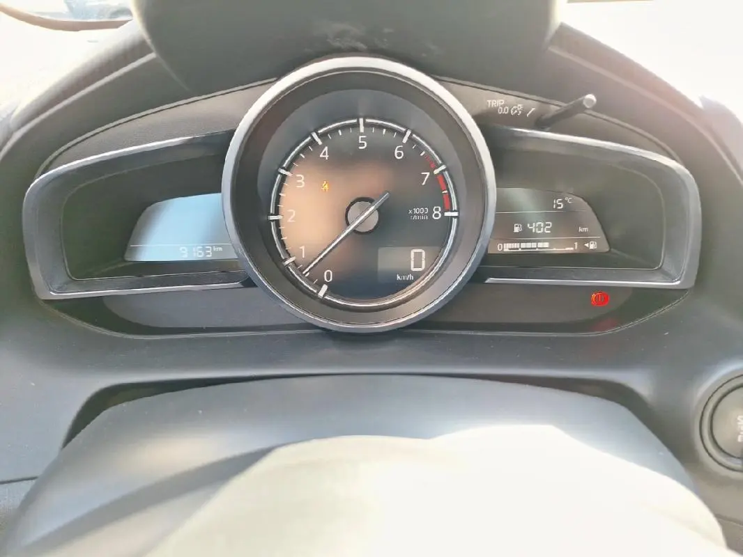 Vue rapprochée du tableau de bord de la Mazda2 2023, affichant le compte-tours central et l'ordinateur de bord.