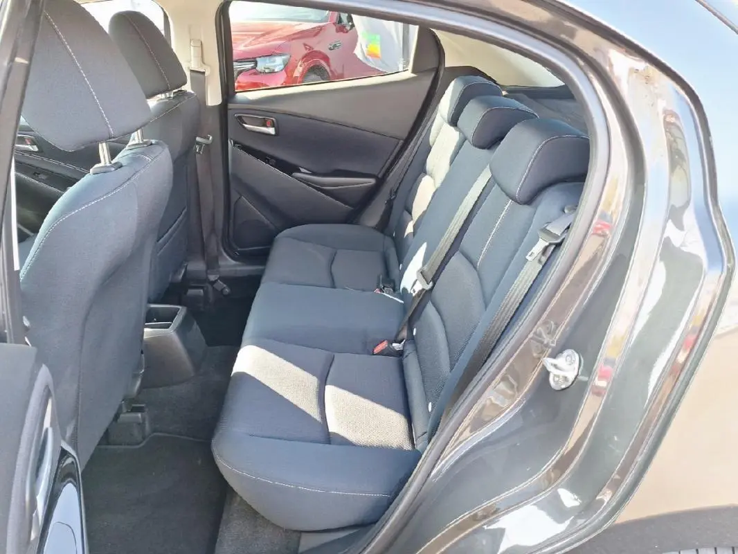 Vue côté gauche arrière sur les sièges arrière gris foncé de la Mazda2 2023 avec portes ouvertes.