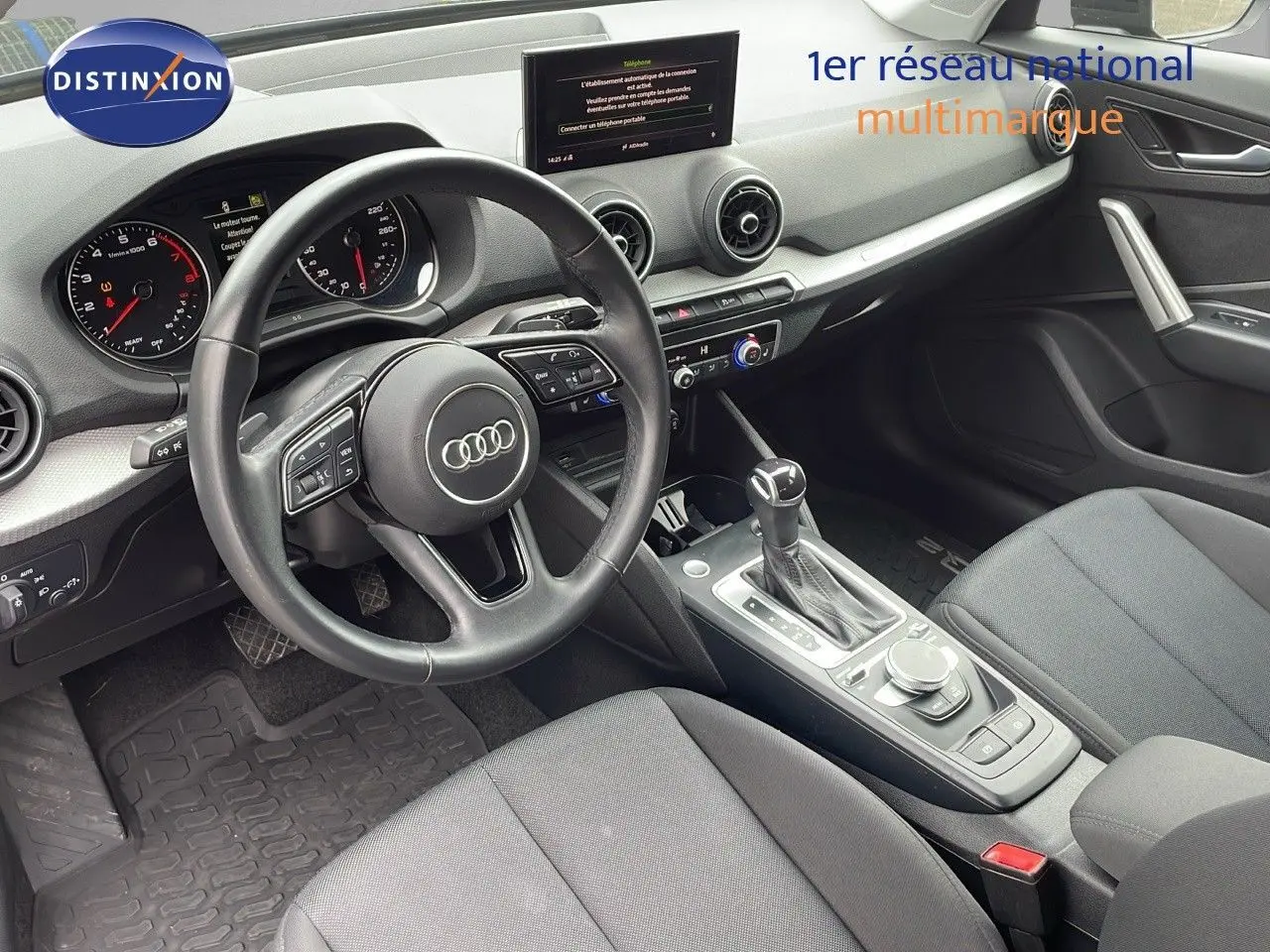 Intérieur de l'Audi Q2 35 TFSI 2023 vu côté conducteur, avec volant multifonction et console centrale moderne.