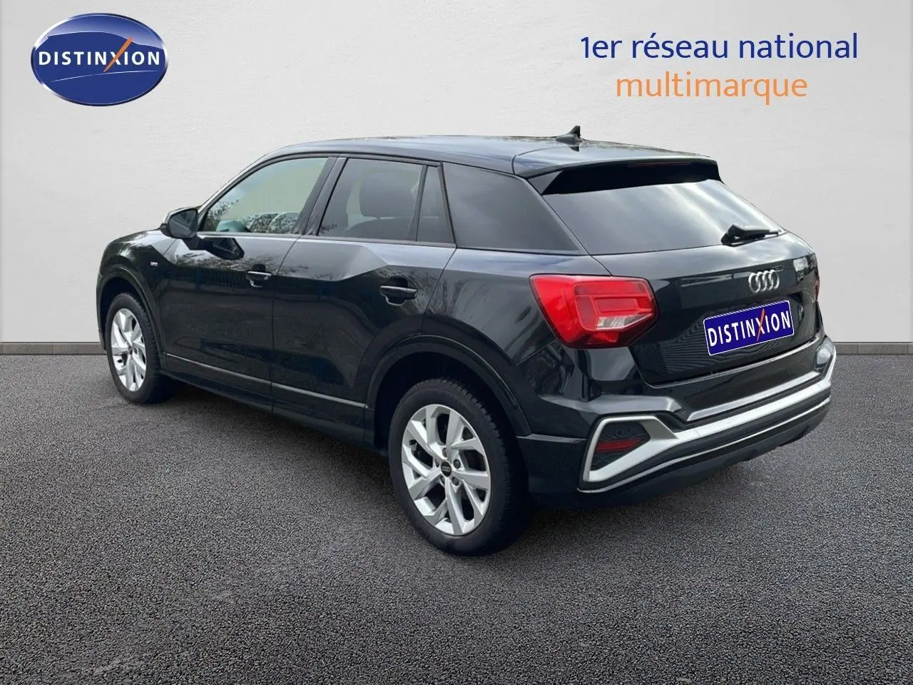 Audi Q2 noir mito metal vue 3/4 arrière côté droit, avec jantes argentées et feux arrière rouges visibles.