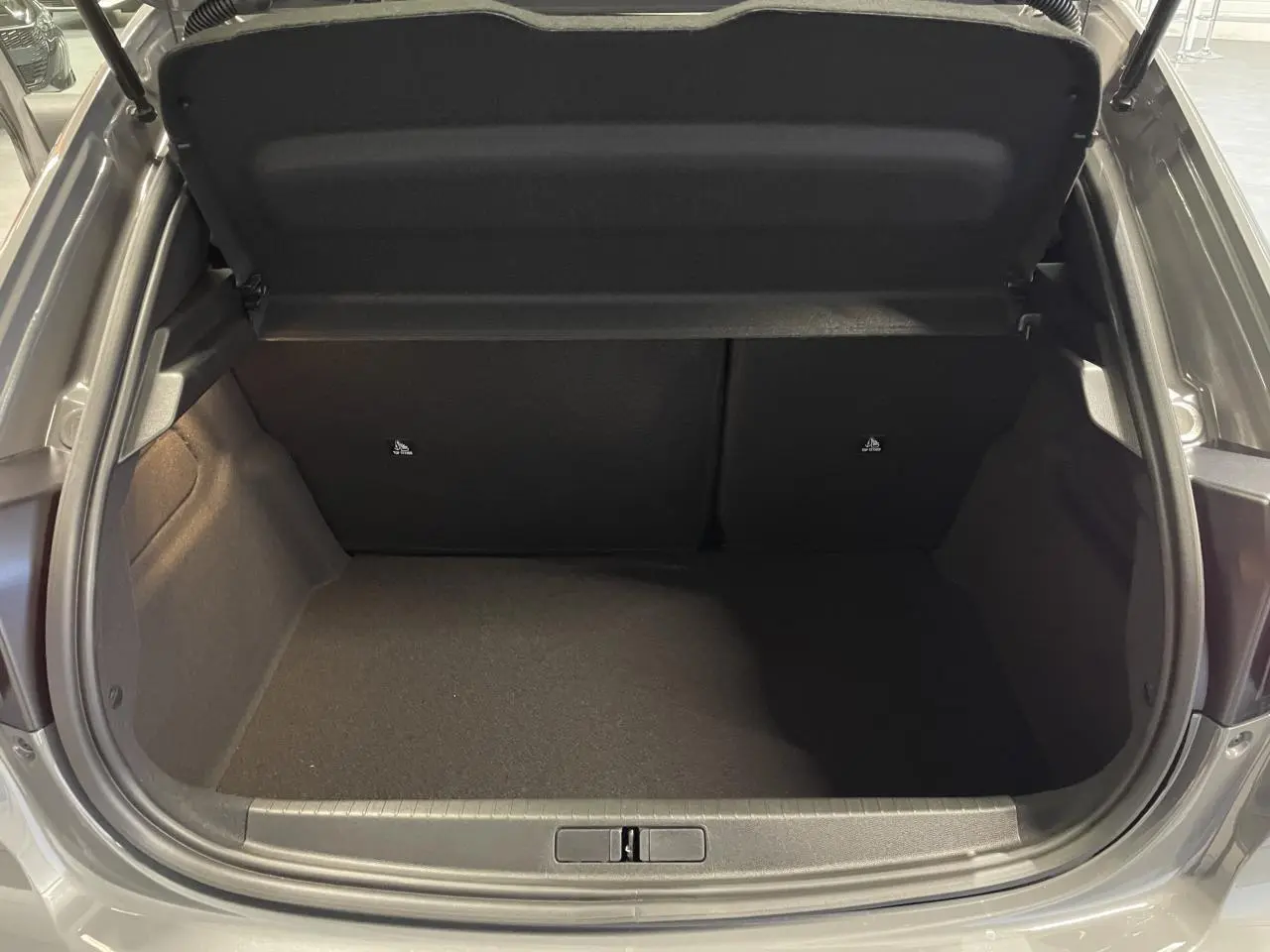 Coffre ouvert de la Peugeot 208 gris selenium, vue arrière montrant l'espace de chargement vide.