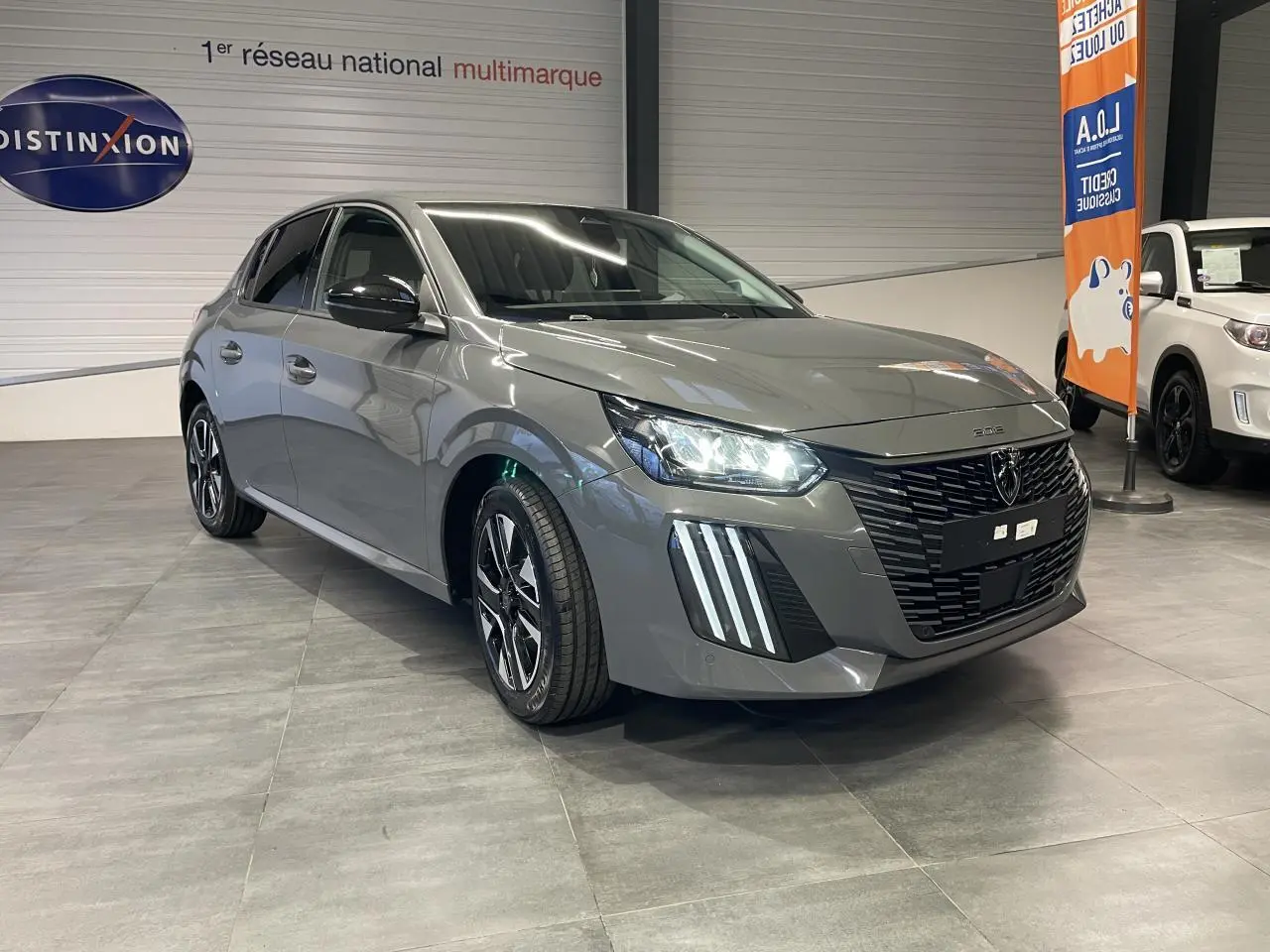 Peugeot 208 gris Selenium vue 3/4 avant avec calandre noire et feux LED à signature verticale.