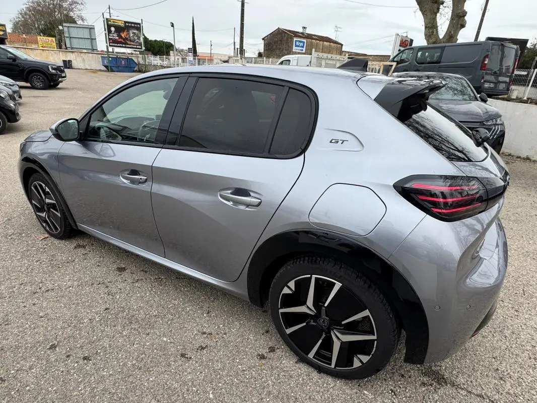 Vue 3/4 arrière droite d'une Peugeot 208 GT gris métallisé avec jantes alliage 17 pouces et antenne requin.