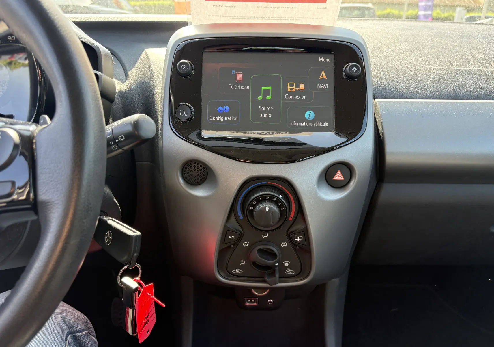 Vue intérieure centrée sur la console centrale et l’écran tactile d’une Toyota Aygo MC blanche de 2020.