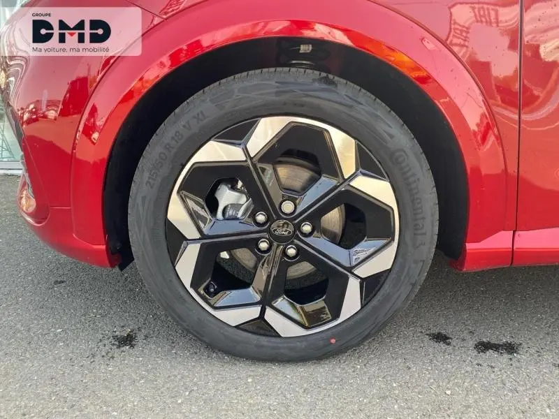 Gros plan sur la roue avant droite avec jante alu noire et argentée du Ford Puma rouge métallisé.