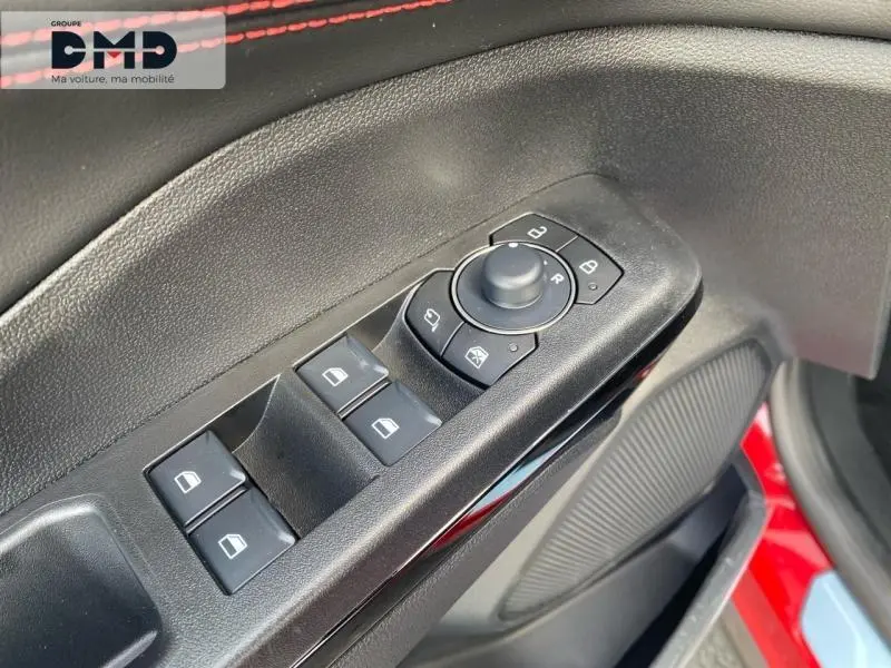 Gros plan sur les commandes de lève-vitres et rétroviseurs côté conducteur du Ford Puma rouge, avec surpiqûres rouges visibles.
