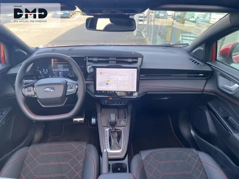 Vue intérieure avant du Ford Puma rouge avec tableau de bord moderne, écran tactile central et volant multifonction.