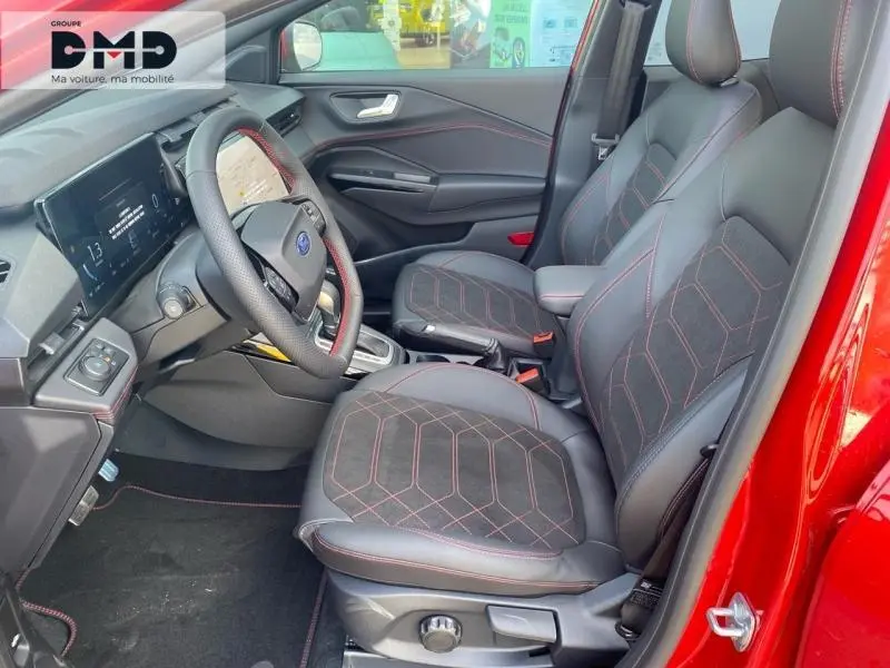 Vue intérieure côté conducteur du Ford Puma rouge, sièges sport noirs avec surpiqûres rouges et volant multifonction.