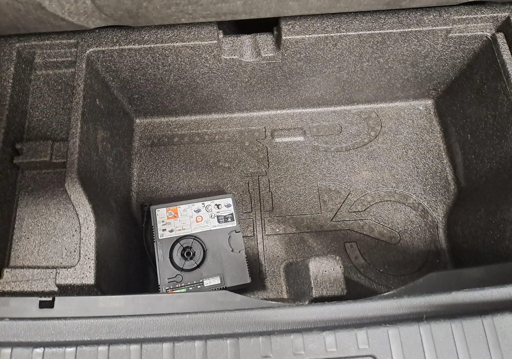 Coffre de rangement sous plancher dans une Skoda Octavia Combi 2024, compartiment vide avec kit de réparation pneus.