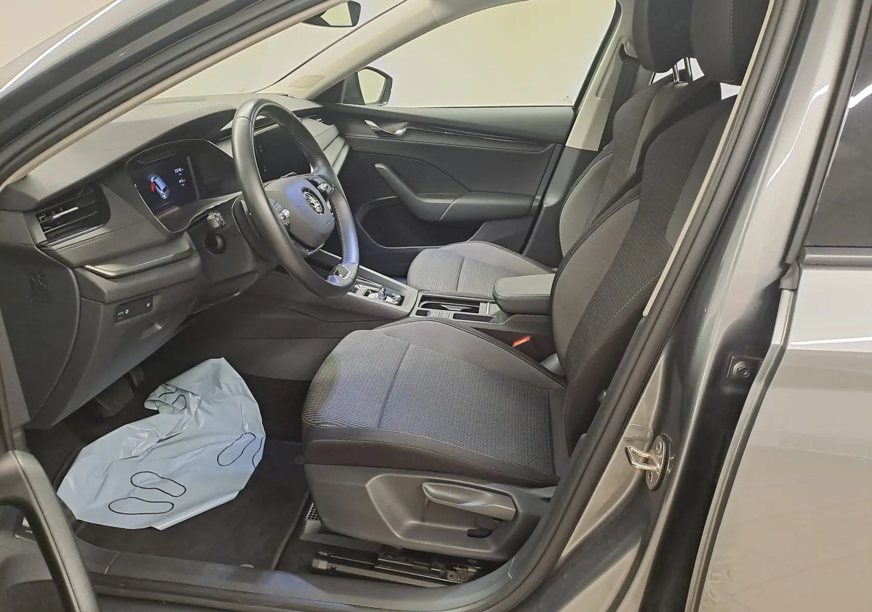 Intérieur côté conducteur de la Skoda Octavia Combi 2024 gris graphite, montrant sièges tissu et tableau de bord moderne.