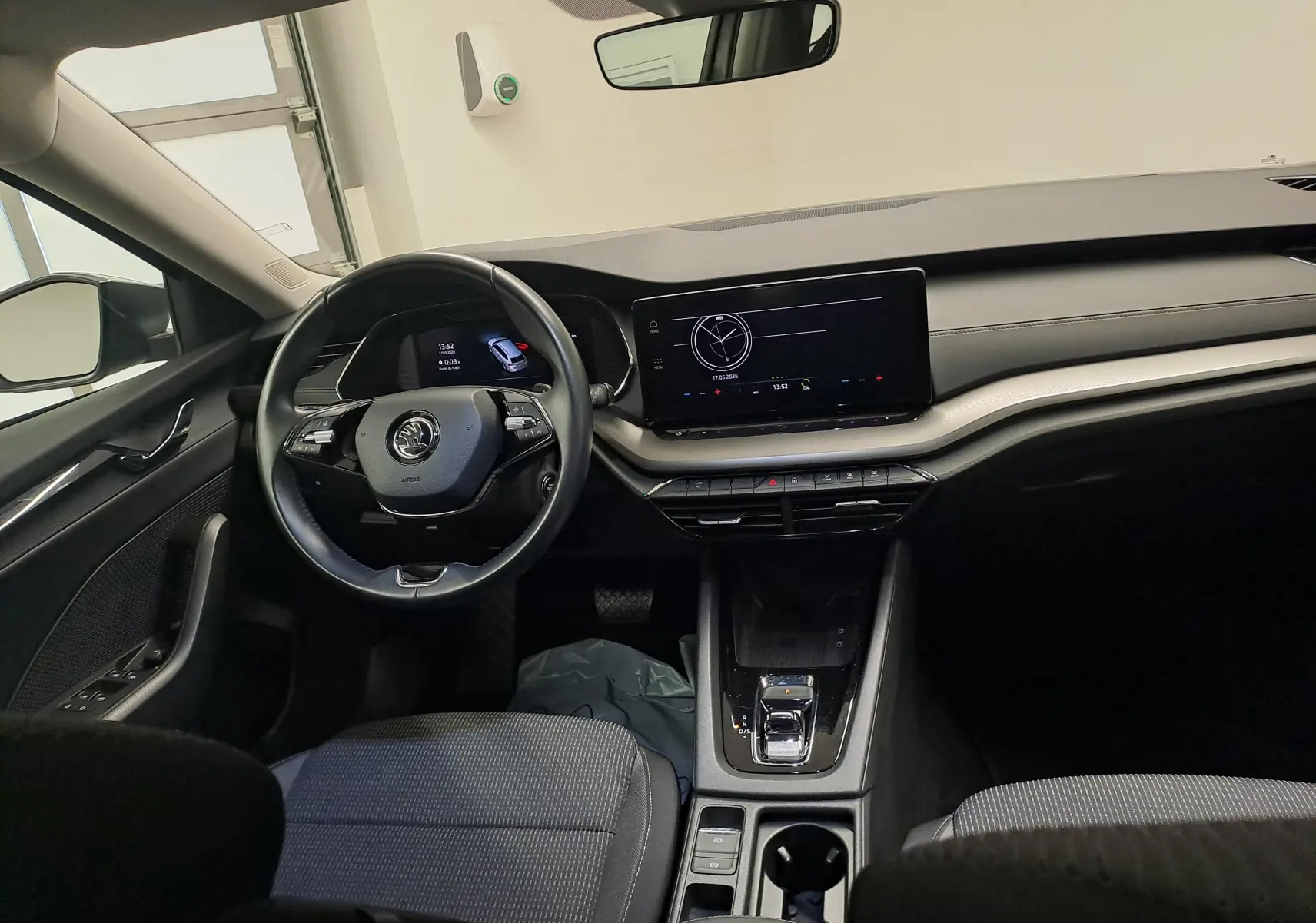Vue intérieure avant de la Skoda Octavia Combi 2024, tableau de bord moderne avec écran tactile et volant multifonction noir.