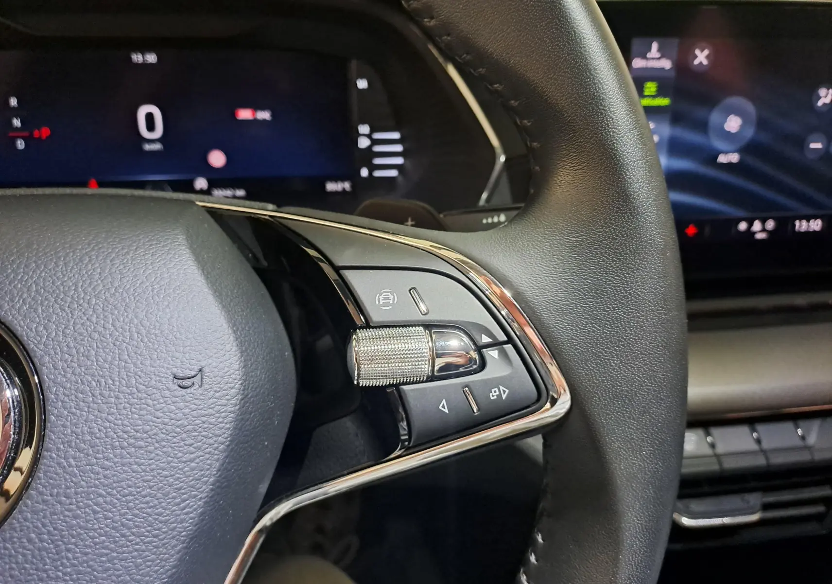 Gros plan sur la partie droite du volant en cuir noir de la Skoda Octavia Combi 2024 avec commandes et molette chromée.