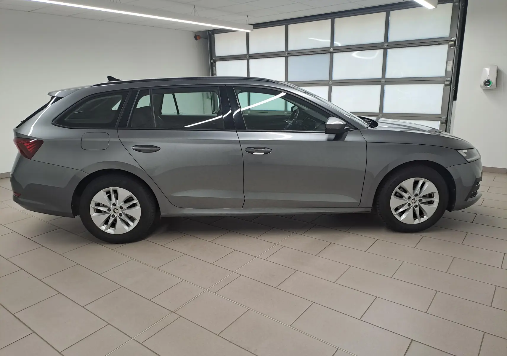 Skoda Octavia Combi 2024 gris graphite vue de profil côté gauche dans un garage lumineux.