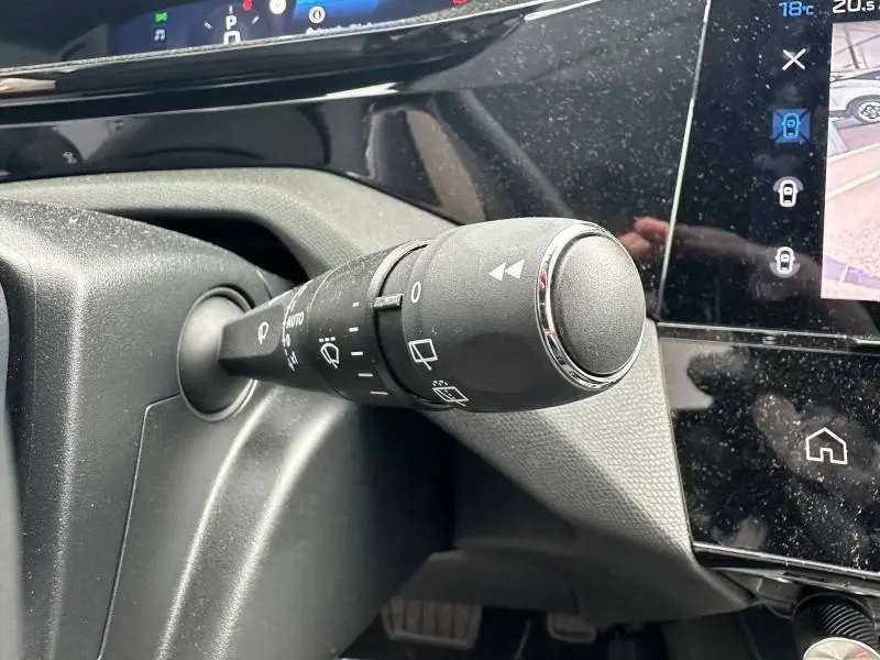 Gros plan sur la commande des essuie-glaces dans l’habitacle d’une Peugeot 308 blanche, avec écran tactile visible.