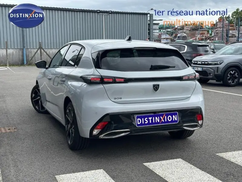 Vue 3/4 arrière droite d'une Peugeot 308 blanche Okénite avec feux arrière LED et jantes alliage noires.