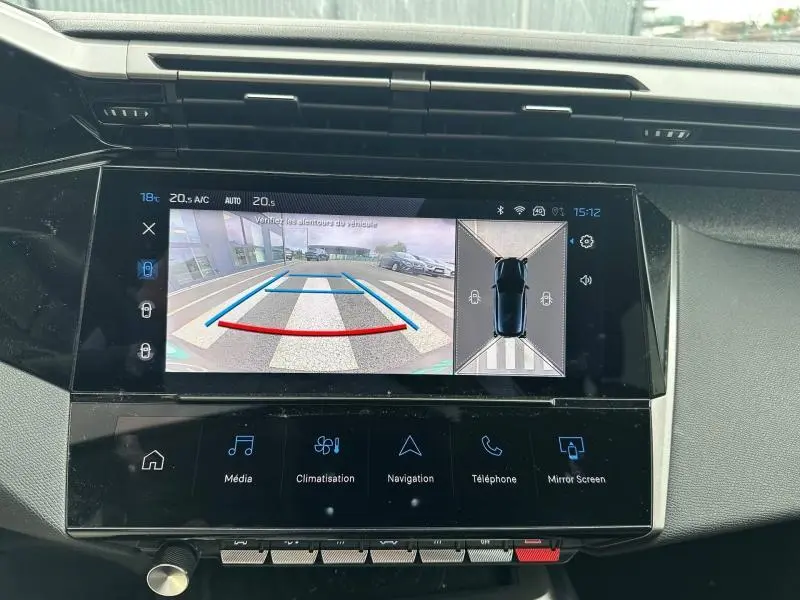 Vue rapprochée de l’écran tactile du tableau de bord affichant la caméra de recul et l’aide au stationnement du Peugeot 308 blanc.