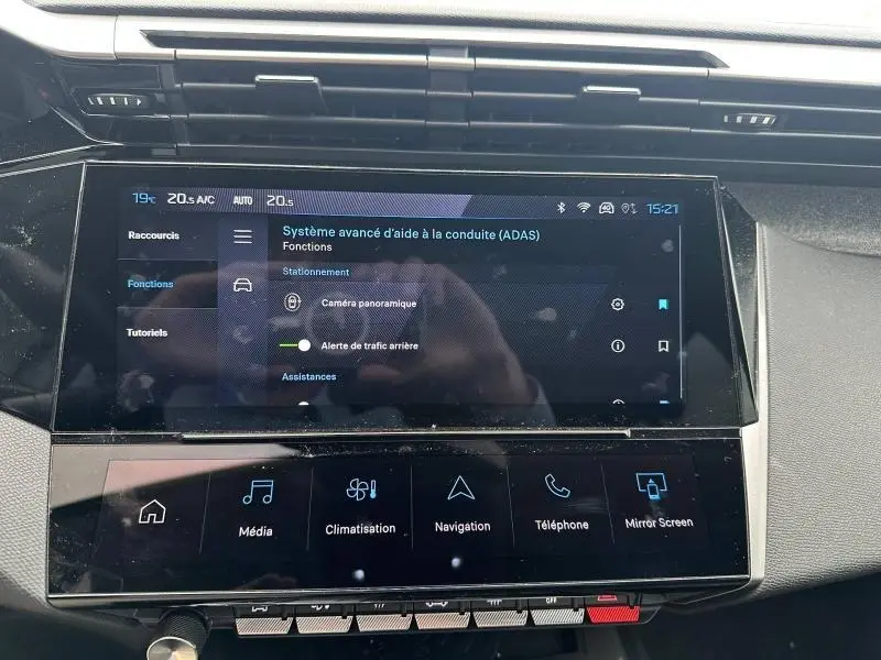 Vue rapprochée de l'écran tactile central du Peugeot 308 blanc Okénite, affichant les aides à la conduite avancées.