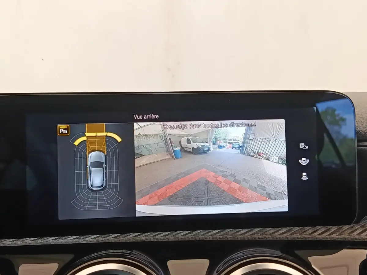 Écran tactile intérieur montrant la caméra de recul et l’aide au stationnement de la Mercedes Classe A gris clair.