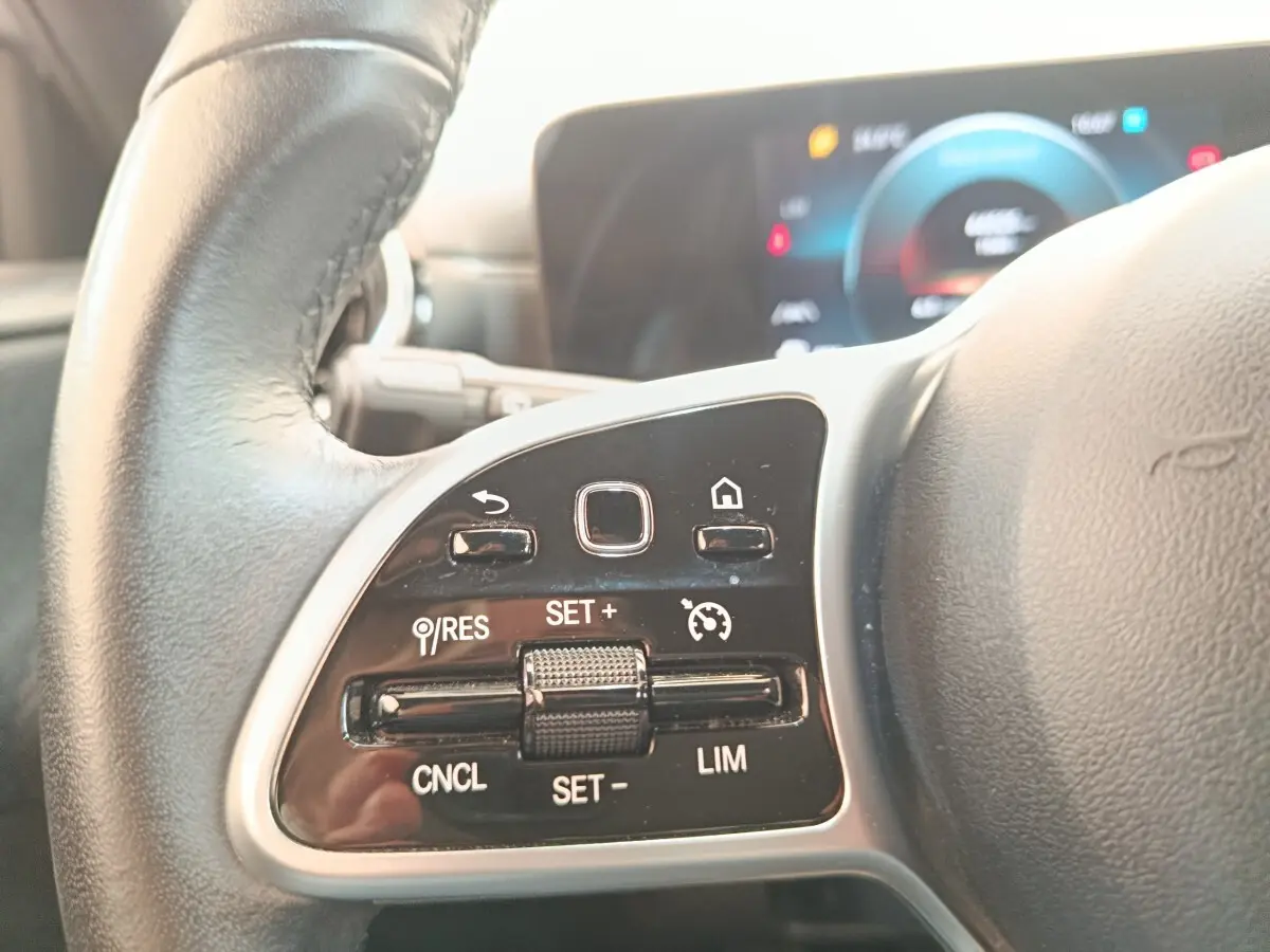 Gros plan sur le volant cuir noir de la Mercedes Classe A 180 d Business Line avec commandes multifonctions côté gauche.