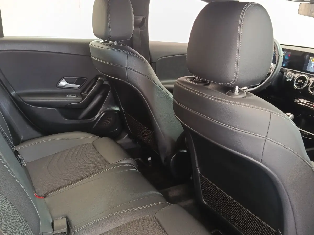 Vue intérieure arrière droite de la Mercedes Classe A 180 d Business Line avec sièges en cuir noir et tableau de bord visible.