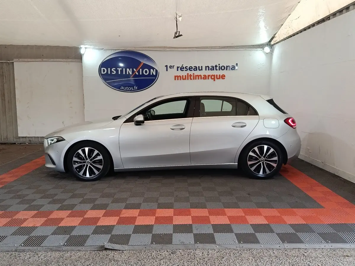 Vue de profil côté gauche d'une Mercedes Classe A 180 d Business Line gris clair dans un showroom.